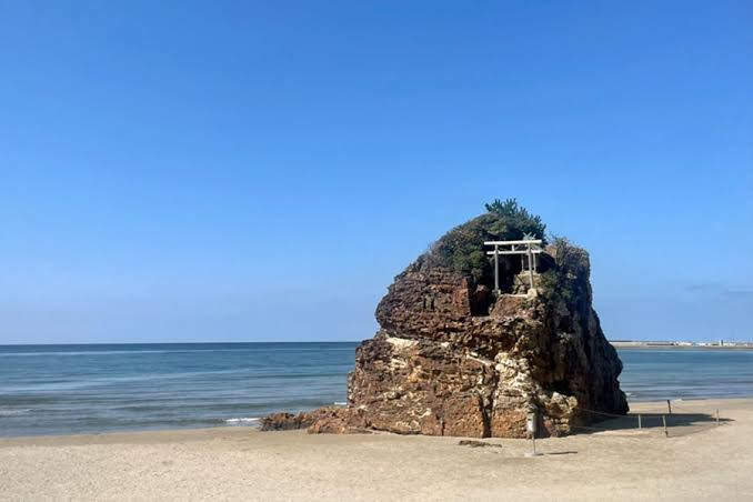Bentenjima, a small torii gate standing atop a rock beyond the sandy beach