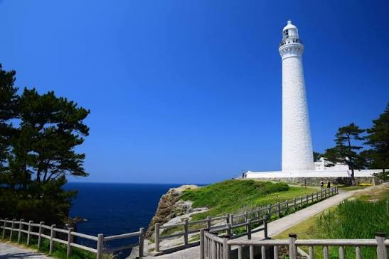The white Hinomisaki Lighthouse standing on a coastal bluff