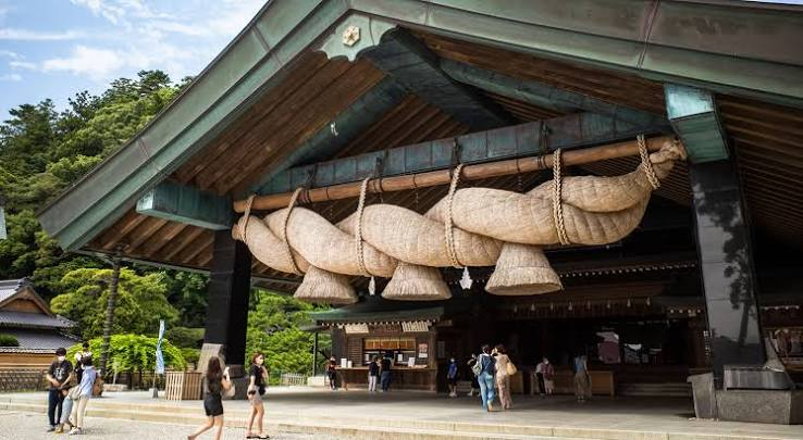 One of Japan's largest shimenawa ropes hanging at the Kagura Hall, with worshippers walking beneath it