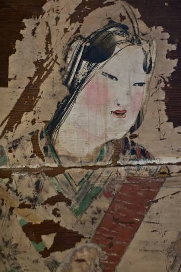 A faded, flaking fragment of an old votive painting depicting a figure